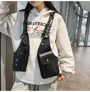 Detailed view of a sleek black tactical vest chest bag styled over a grey hooded sweatshirt.