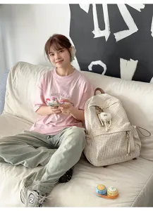 Minimalist plaid backpack for students shown in a cozy lifestyle setting on a sofa