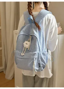 Close-up of a student wearing a light blue Japanese style grid backpack with a cute charm