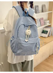 Detailed view of a light blue plaid backpack featuring a cute white plush pendant