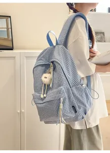 Detail shot of a light blue checkered backpack worn by a model in a bright room.