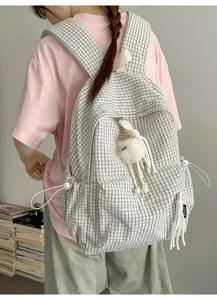 Back view of a student wearing a stylish plaid backpack featuring a cute plush charm accessory