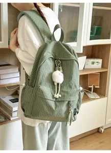 Detail view of a green checkered backpack with a cute white plush keychain charm