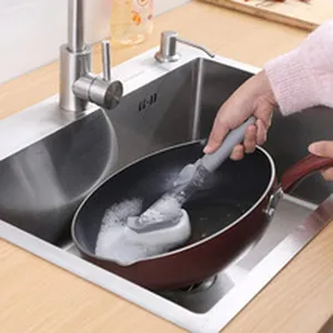 Close-up of cleaning wand removing grease and stains from a frying pan in a sink.