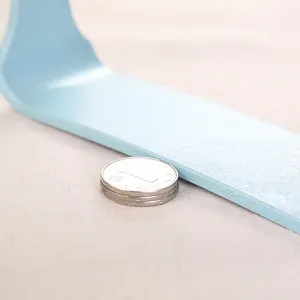 Close-up macro view showing the thickness of a light blue desktop mirror base with coins