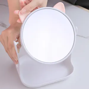 Minimalist white desktop makeup mirror with pink cat ears on a clean marble surface