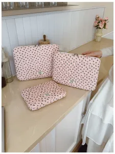 Detail view showing three quilted pink floral sleeves for tablets and laptops in a home setting.