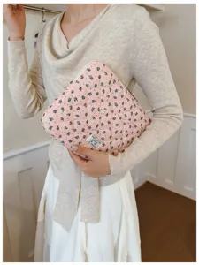Close-up detail of a pink floral quilted laptop sleeve held by a person indoors.