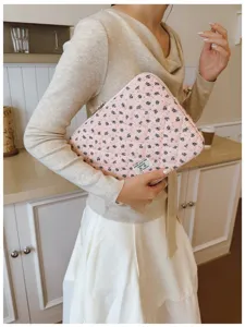 Detail view of a stylish pink quilted laptop sleeve with delicate blue floral patterns