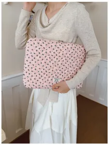 Close-up of a stylish floral quilted laptop sleeve held by a woman in a casual setting