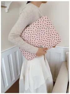 Close-up view of a stylish pink floral laptop sleeve held by a woman in lifestyle setting