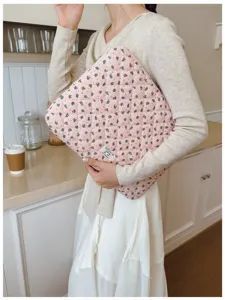 Close-up of a model holding a pink floral quilted laptop sleeve in a cozy kitchen setting