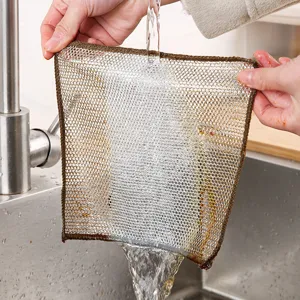 Silver wire mesh dishcloth being rinsed under kitchen faucet for cleaning.