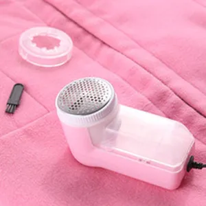 Close-up view of pink electric fabric shaver and accessories on clothing
