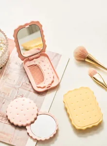 Close-up of biscuit-shaped folding makeup mirrors and combs with soft pastel colors.