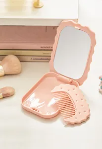 Detailed view of the pink biscuit-shaped portable folding makeup mirror with comb