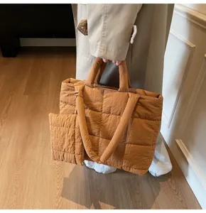 Model met een bruine gewatteerde katoenen draagtas die het zachte ontwerp laat zien.