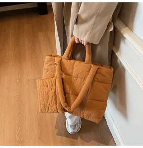 Details van bruine gewatteerde puffer-tas gedragen met een beige jas
