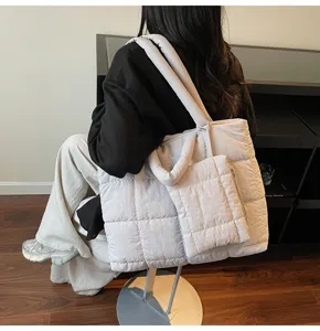 Lifestyle-detail van een vrouw die een stijlvolle lichtgekleurde gewatteerde tas draagt