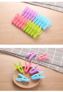 Assorted colorful plastic clothespins for laundry, displayed on a wooden table.