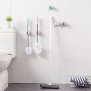 Wall-mounted toilet brushes and squeegee hanging neatly in a modern white bathroom.