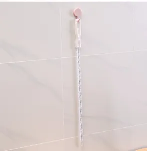 Vue détaillée d'un long goupillon flexible accroché sur un mur carrelé blanc pour rangement
