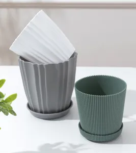 Detailopname van geribbelde plastic bloempotten in wit, grijs en groen met schotels