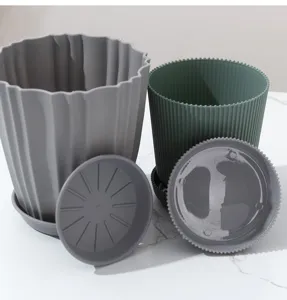 Gedetailleerde weergave van grijze en groene geribbelde plastic bloempotten met schotels.