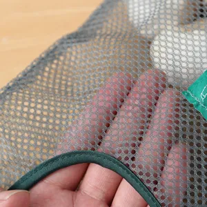 Gros plan sur un sac de rangement suspendu en filet gris pour fruits et légumes de cuisine
