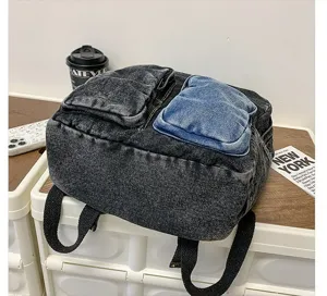 Vintage denim backpack with blue pocket detail displayed on a modern lifestyle desk