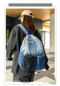 Stylish ombre blue denim backpack worn by a model in an urban outdoor street setting