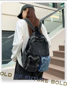 Detailed back view of a stylish black denim backpack with a blue contrast pocket on model