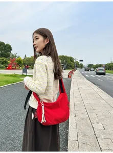 Detaillierte Outdoor-Lifestyle-Ansicht einer roten Canvas-Halbmondtasche an einem Model