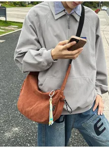 Detailansicht der rostbraunen Cord-Umhängetasche an einem Model im lässigen Outdoor-Stil