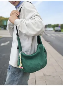 Detail einer grünen Cord-Hobo-Tasche, die von einem Modell im Freien getragen wird.