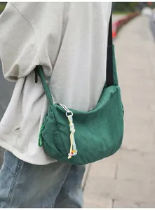 Detailansicht einer grünen Umhängetasche aus Cord mit einem kleinen bunten Anhänger