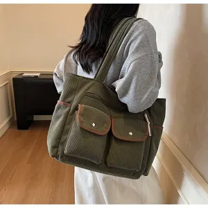 Female model carrying a large green corduroy commuter tote bag with multi-pocket details