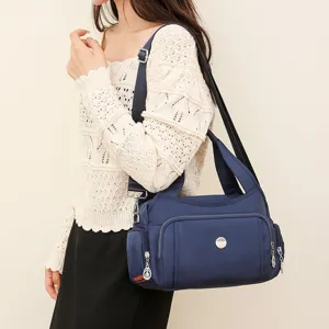 Detailed macro view of the navy blue waterproof nylon shoulder bag carried by a model