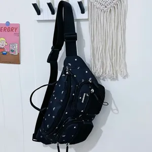 Detail view of black nylon chest bag with white star pattern and multiple zippers for women