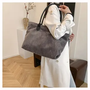 Detailweergave van grijze corduroy draagtas gedragen met een witte trenchcoat