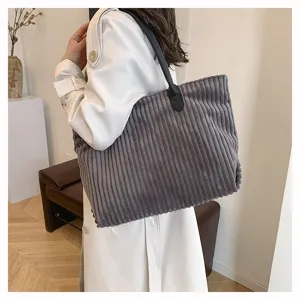 Detailweergave van een grote grijze corduroy draagtas gedragen over de schouder