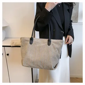 Stijlvolle beige corduroy draagtas met grote capaciteit getoond op een vrouwelijk model voor werk