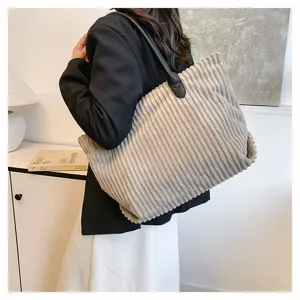 Gedetailleerd overzicht van een grote beige corduroy draagtas gedragen door een model.