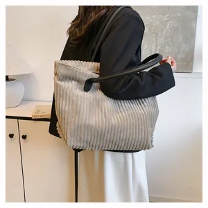 Gedetailleerde weergave van beige corduroy draagtas met zwarte hengsels in lifestyle-setting