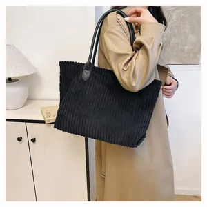 Grote zwarte corduroy draagtas voor dames over de schouder gedragen, lifestyle