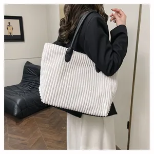 Detailopname van een witte corduroy draagtas met grote capaciteit en ribbeltextuur.