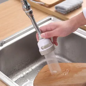 Detail van een 360 graden draaibare keukenkraanverlenging die water op een plank spuit.