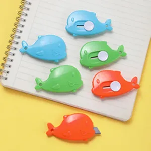 Lindos mini cúteres con forma de ballena en azul, verde y naranja sobre un cuaderno de notas.