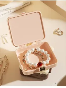 Detailansicht einer offenen rosa tragbaren Schmuckschatulle mit eleganten Perlenarmbändern