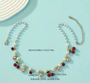 Dettaglio macro di ciondoli a ciliegia rossa e cuore d'oro su collana di perle